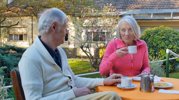 Кавказская пара на пенсии завтракает в саду. Концепция ухода на пенсию и отдыха. - Фото, изображение