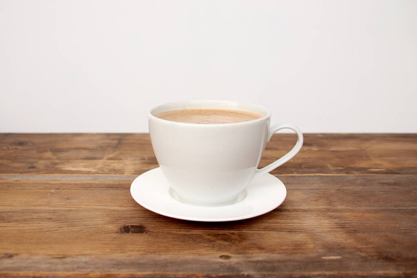 Капучино кофе в белой чашке и блюдце на старом деревянном столе, концепция стильного кафе
 - Фото, изображение