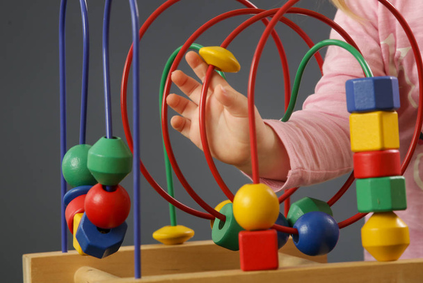 Pikkulapsi tyttö leikkii lanka helmi sokkelo lelu. Tämä värikäs koulutus puinen lelu opettaa lapsille käsi-silmä-koordinointia, motorisia taitoja ja värejä
. - Valokuva, kuva