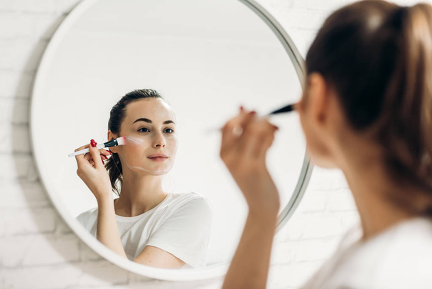 Beautiful young woman applying makeup in bathroom. - Foto, immagini