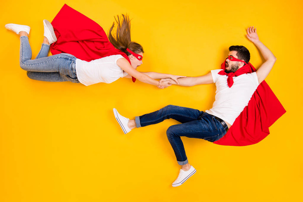 Top view above high angle flat lay flatlay lie view concept of funny clumsy awkward superheros flying catching each other isolated on bright vivid shine vibrant yellow color background - Photo, image