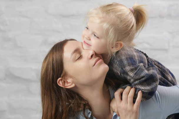 Pequeña niña jugando suavemente y abrazándose con su mamá
 - Foto, Imagen