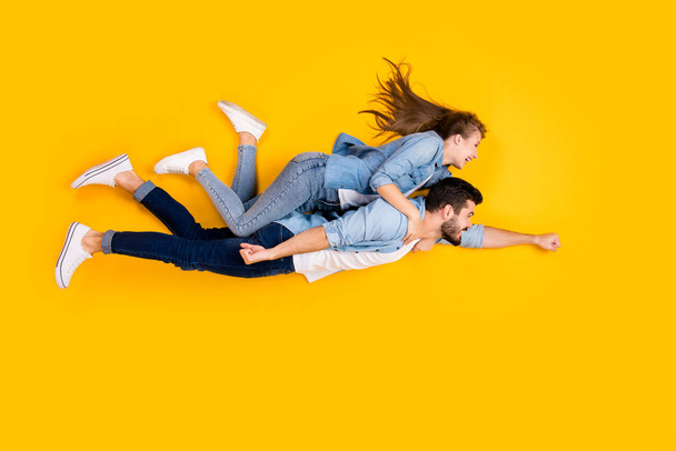 Top view above high angle flat lay flatlay lie full length body size view concept of cheerful beautiful handsome spouses flying embracing isolated on bright vivid shine vibrant yellow color background - Fotó, kép