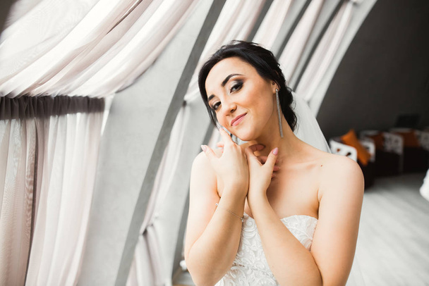 Luxusní nevěsta v bílých šatech pózuje při přípravě na svatební obřad - Fotografie, Obrázek