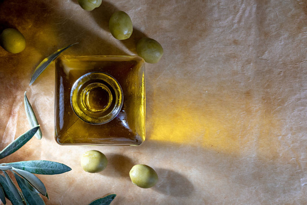 Olio extra vergine di oliva in bottiglia di vetro. Include foglie di ulivo e rami. Sfondo rustico. Vista dall'alto
. - Foto, immagini