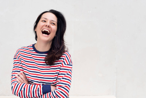 Portrait de jeune femme heureuse riant avec les bras croisés par fond blanc
 - Photo, image