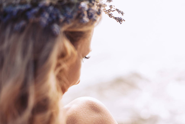 A girl with a bare shoulder and a wreath on her head enjoys relaxing on a hot sunny day. Blurred background. - Fotó, kép