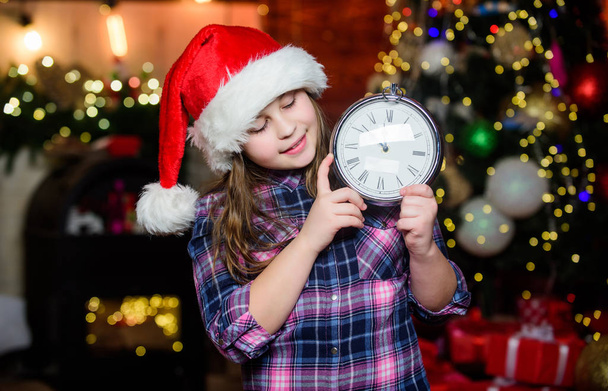 Are you ready. Time to celebrate. Happy new year. Elf child with clock. Xmas tree. Happy holiday. Little girl in red hat. Happy christmas. Santa claus little girl. Christmas interior. Christmas time - Foto, imagen