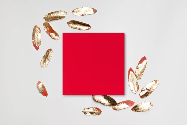 Marco de papel rojo mínimo con hojas de oro sobre un fondo gris
. - Foto, imagen