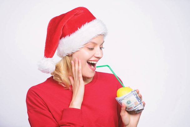Lemon money concept. Girl santa hat drink juice lemon wrapped in banknote. Totally natural lemon juice. Fresh lemonade drink with straw. Symbol of wealth and richness. Girl with lemon and money - Photo, Image