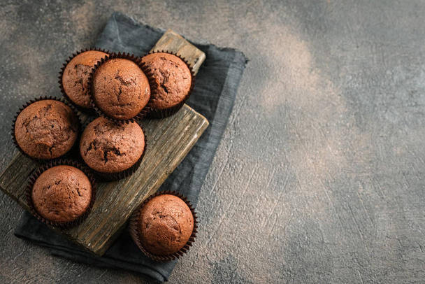 Chocolate muffins on a portioned board on a dark background top view copy space. - Φωτογραφία, εικόνα