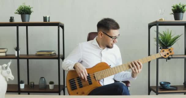 Businessman is playing on guitar and enjoying it sitting in office during break. - Video