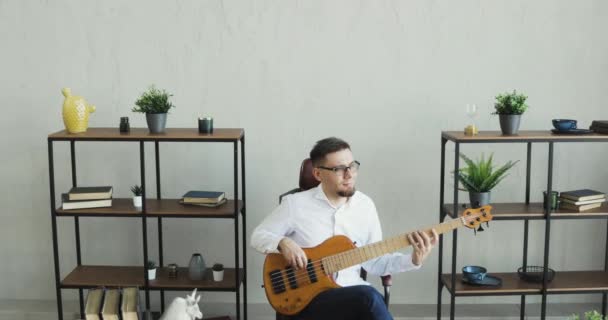 Office worker is playing on guitar and enjoying it sitting at work during break. - Záběry, video