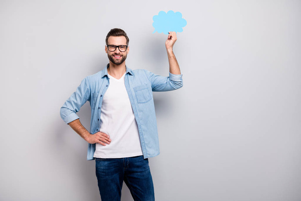 Photo of attractive guy holding blue empty paper cloud showing funny dialogue answer expressing mind mood wear specs casual denim outfit isolated grey color background - Foto, immagini