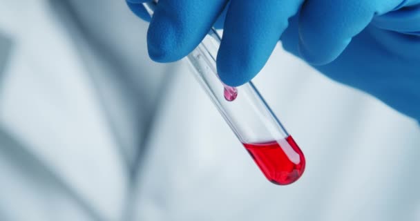Travailleur médical du laboratoire examine attentivement le sérum dans un tube de verre
 - Séquence, vidéo