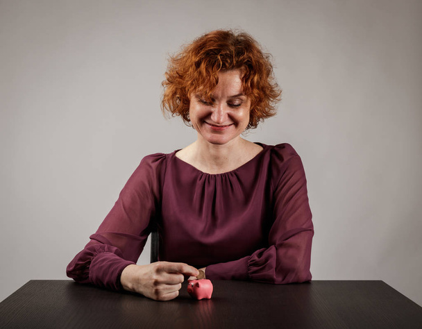 Red-haired woman and piggy bank. - Fotografie, Obrázek