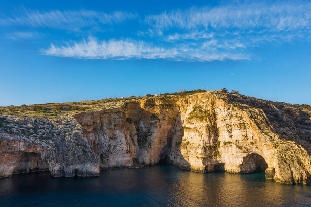 Letecký pohled na Modrou jeskyni, jeskyně, útesy. Modrá jasná obloha s mraky, zima, skály. Malta country - Fotografie, Obrázek