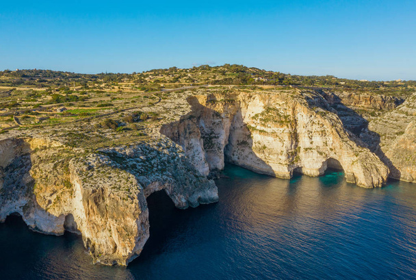 Vista aérea da gruta azul, cavernas, falésias e barco. Céu azul claro, rochas. Malta
  - Foto, Imagem