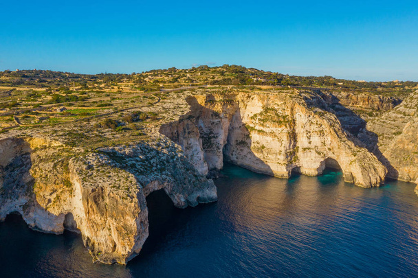 Letecký pohled na Modrou jeskyni, jeskyně, útesy a loď. Modrá jasná obloha, kameny. Malta country - Fotografie, Obrázek