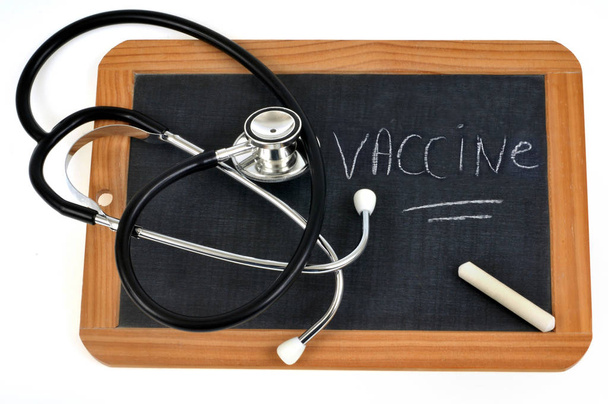 Estetoscópio e giz em uma ardósia de escola na qual se escreve a vacina
  - Foto, Imagem