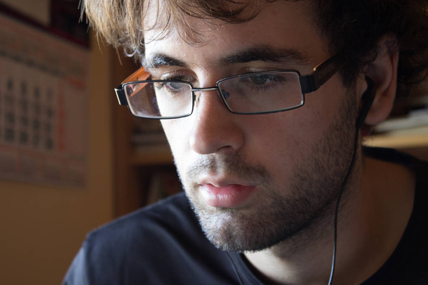 Joven hombre blanco con pelo rizado y gafas en posición de estudio con música. Una foto graciosa. Espacio para texto
. - Foto, imagen