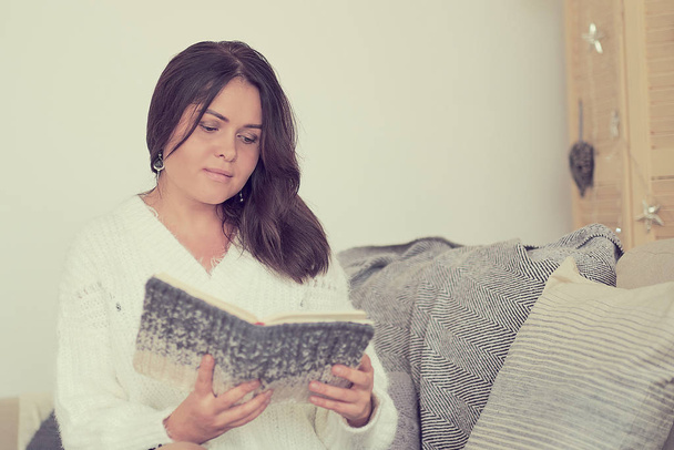 junge Frau las Buch auf Sofa in Lounge. entspanntes Mädchen im warmen Pullover mit einem Buch in der Hand - Foto, Bild