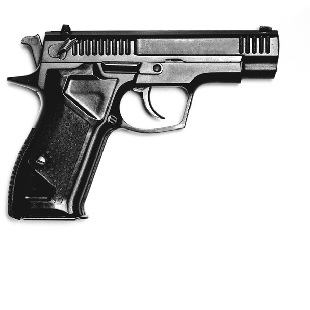 Een zwart pistool ligt tegen een witte achtergrond. Geïsoleerd. Zicht van bovenaf. Close-up - Foto, afbeelding