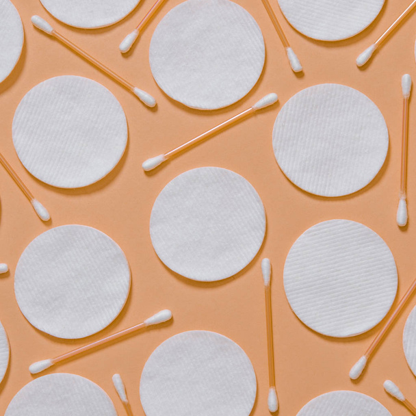 Продукти гігієни: круглі білі ватні подушечки та ватні тампони на кольоровому фоні
 - Фото, зображення