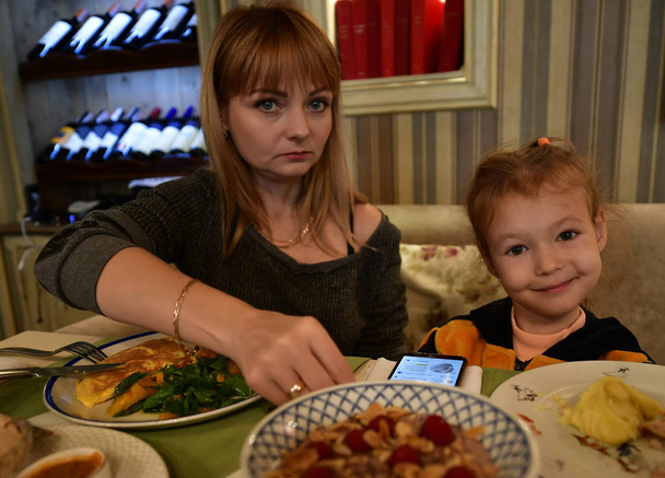 Kaunis kypsä nainen ja hänen pieni tyttärensä ravintolassa
. - Valokuva, kuva