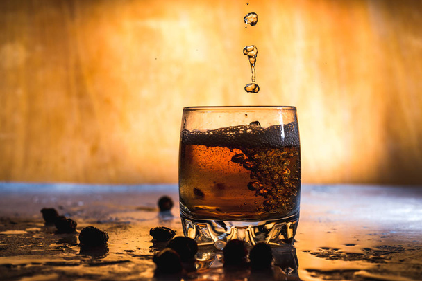  Plons koud ijs in glas whisky geïsoleerd op een lichte achtergrond - Foto, afbeelding
