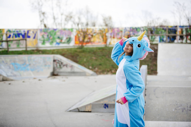 beautiful young woman wearing turquoise unicorn onesie in urban environment - Valokuva, kuva