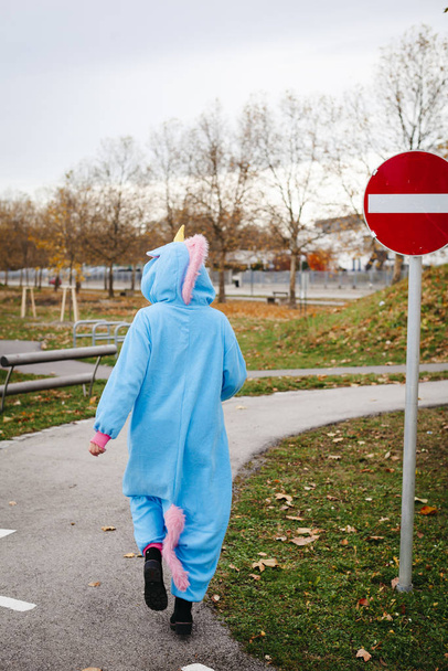 beautiful young woman wearing turquoise unicorn onesie in urban environment - Fotoğraf, Görsel