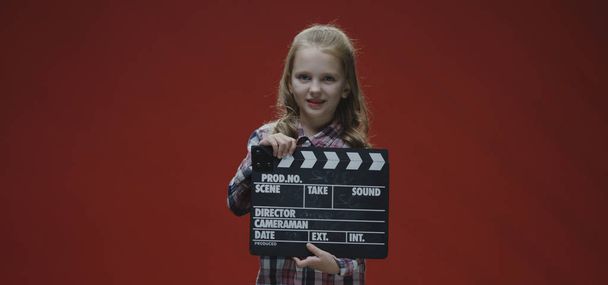 Girl clapping clapboard and raising eyebrows - Photo, Image