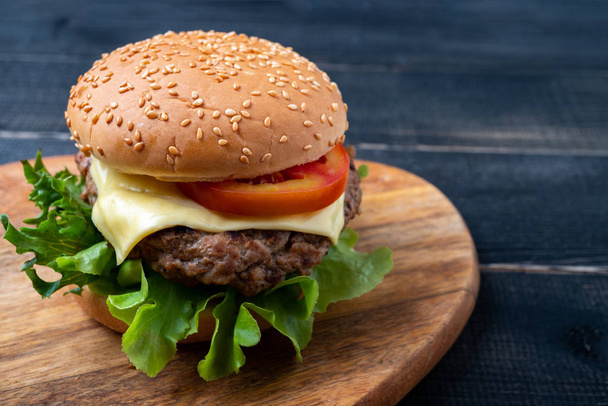 hamburger maison frais savoureux avec légumes frais, laitue, tomate, fromage sur une planche à découper. Espace libre pour le texte - Photo, image