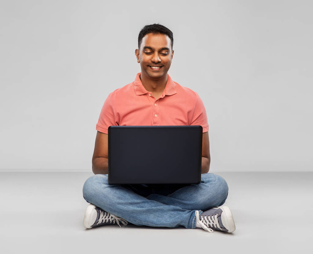 happy indian man with laptop computer on floor - 写真・画像