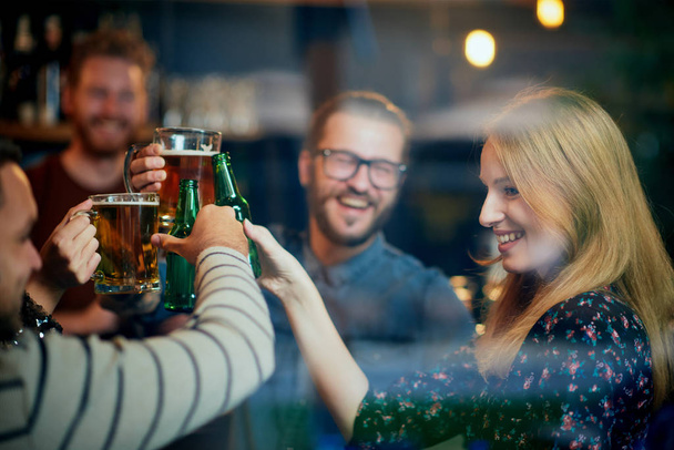 Group of best friends standing at pub and toasting with beer. Nightlife. - Photo, Image
