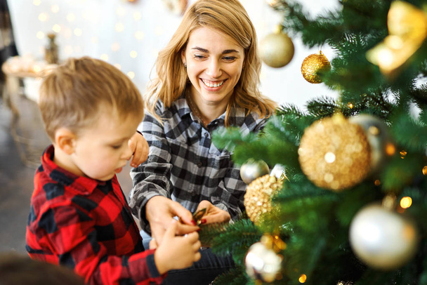 mom and son together decorating Christmas tree on the eve of holidays. - Foto, imagen