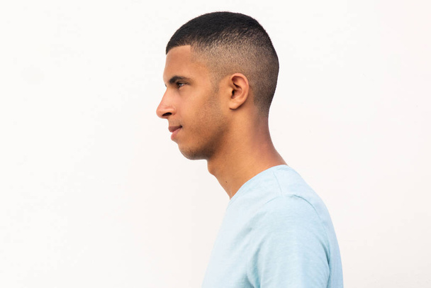 Profiel portret van jonge Noord-Afrikaanse man met serieuze expressie door geïsoleerde witte achtergrond - Foto, afbeelding