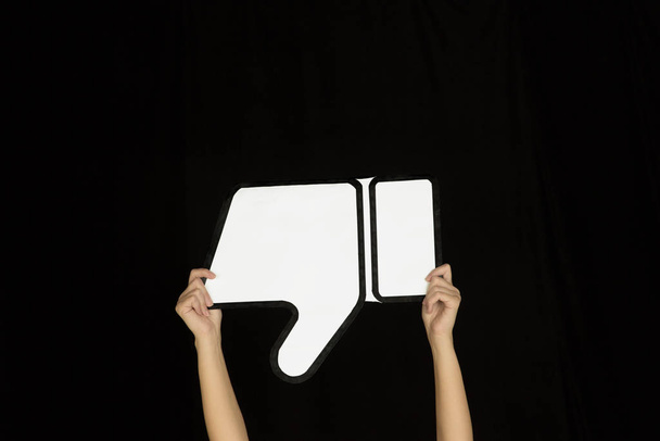 Hands holding the sign of dislike on black studio background - Fotó, kép
