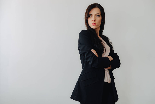 Young attractive emotional girl in business-style clothes on a plain white background in an office or audience - Foto, Imagen