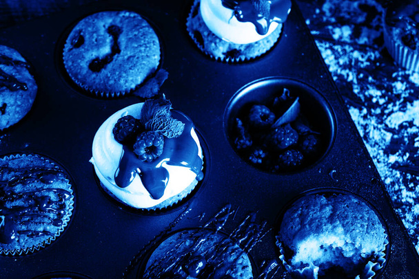青色を基調としたパティシエの手に菓子袋からクリームをコーティングし、カップケーキを作るプロセス - 写真・画像