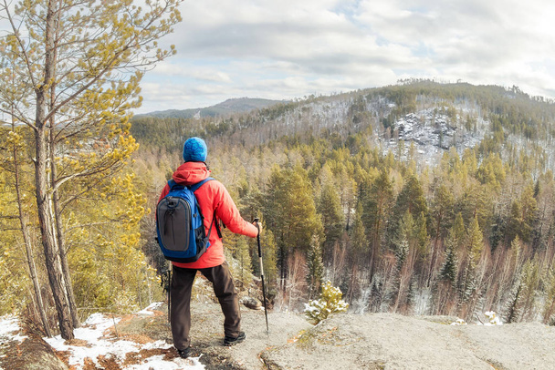 hiker man with a backpack stands on top of a mountain above the forest and looks at the valley - Foto, Bild