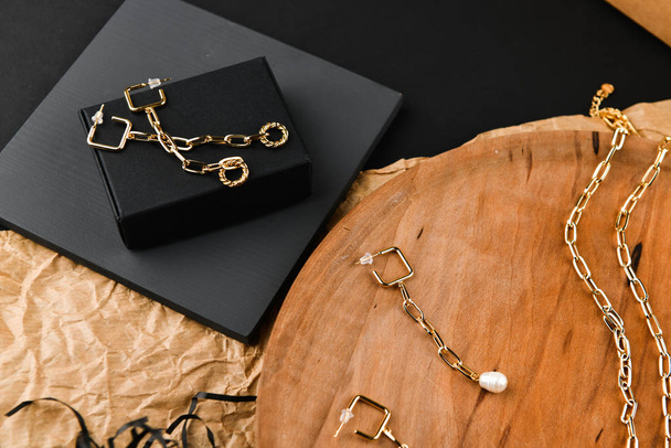 Gouden oorbellen. asymmetrie. Een close-up. Op een houten statief. Zicht van bovenaf. Het concept van juwelen en juwelen. Cadeaus voor vrouwen. winkelen. Handwerk. - Foto, afbeelding