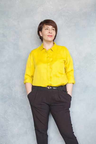 熟女の肖像画。黄色のシャツを着た賢いビジネス女性  - 写真・画像