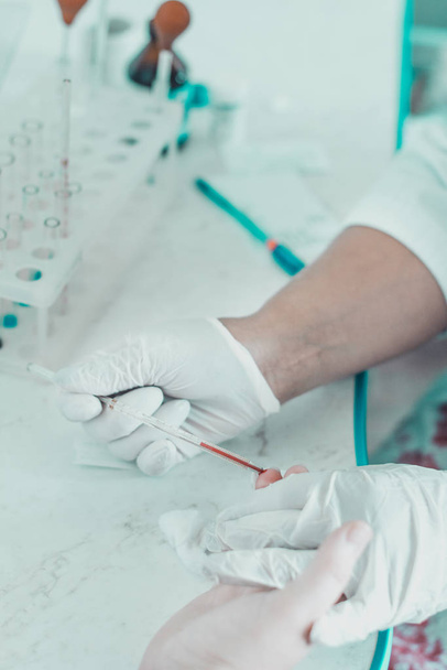 Gros plan de l'échantillonnage sanguin du doigt, du technicien de laboratoire et des mains du patient
. - Photo, image