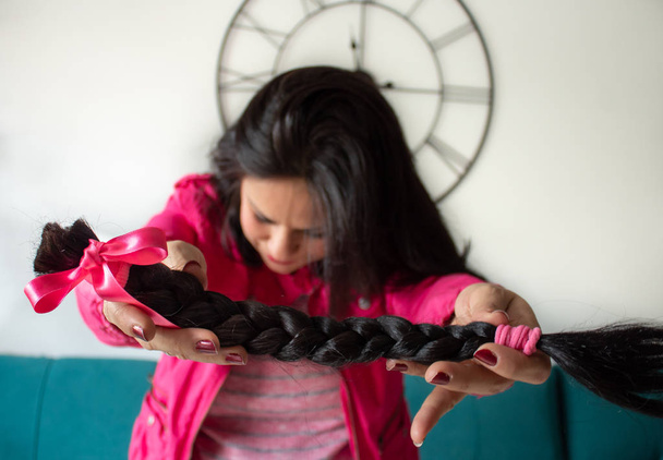 Young woman offering braid hair in solidarity for patients with chemotherapy - Photo, Image