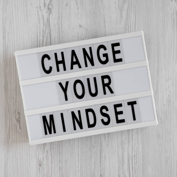'Cambia tu mentalidad' palabras en una caja de luz en una espalda de madera blanca
 - Foto, imagen