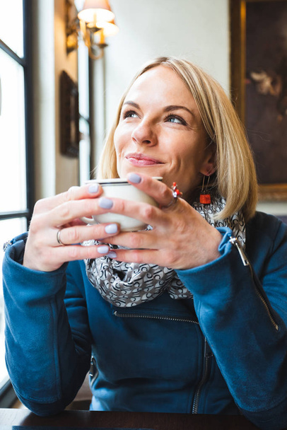 Woman drinking coffee in a cafe - Fotó, kép