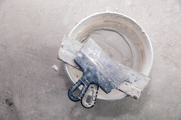 gesso de cimento decorativo e espátula em balde de construção ler
 - Foto, Imagem
