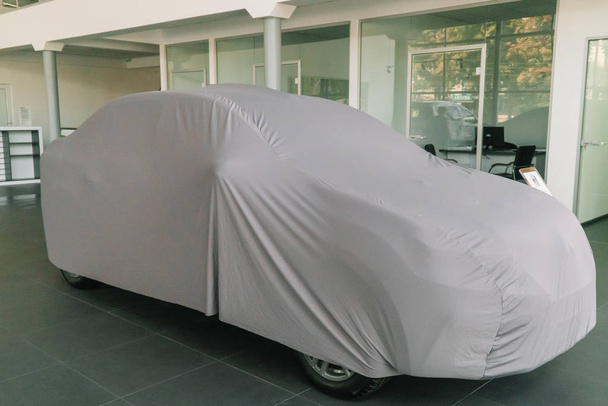 El coche bajo la cubierta protectora está en la sala de exposición
 - Foto, Imagen